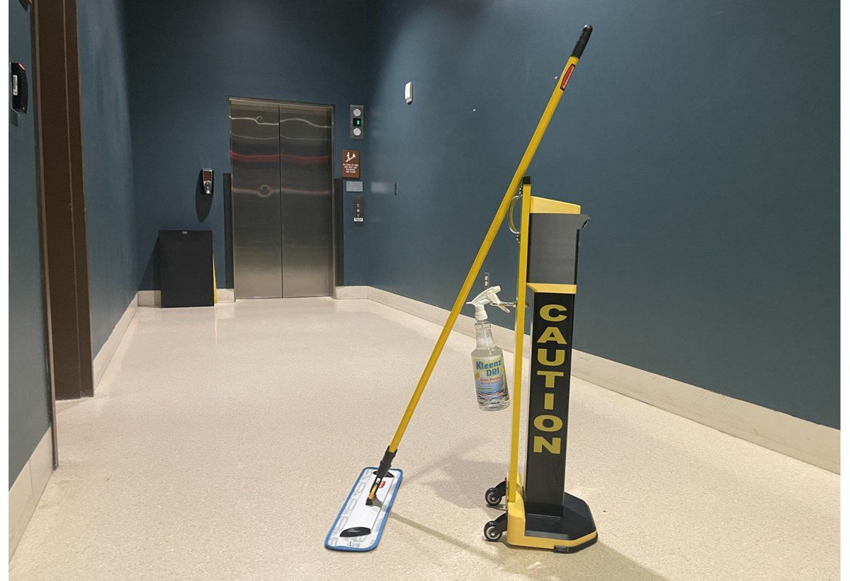 Safety Illuminator Mobile Model with a flat mop and KleenzDRI bottle in a hallway by the elevator